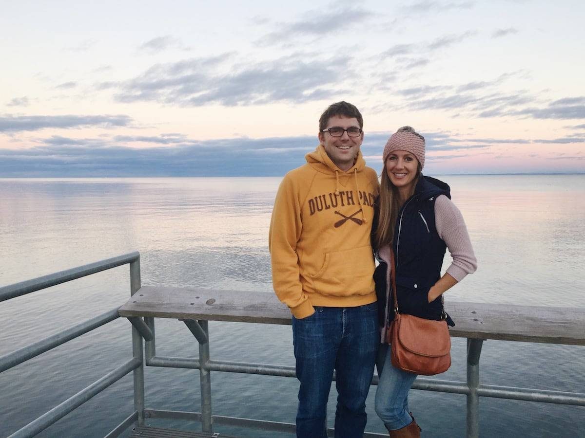 Man and woman standing on a dock over the lake.