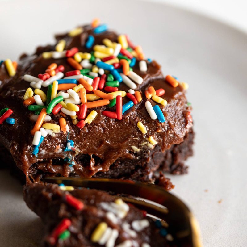 Brownie on a plate with rainbow sprinkles.